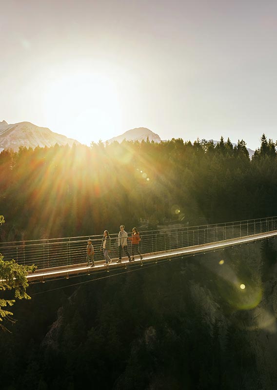 A narrow suspension footbridge stretches across a canyon.