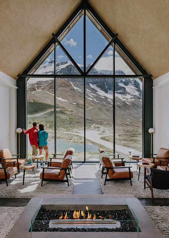 Glacier View Lodge guest lounge with fireplace and floor to ceiling view of the Columbia Icefield