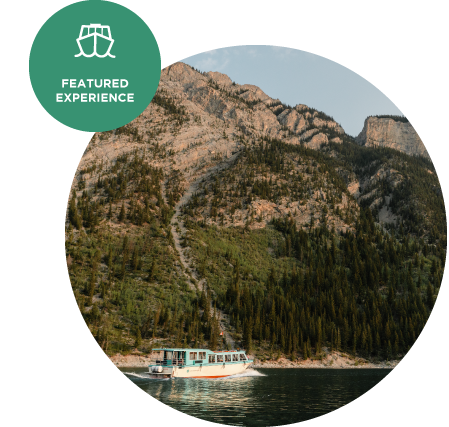 A boat cruises on a lake below a forested mountainside